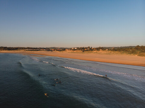 Aerial view of the coast with surfers in the sea during a surf and travel week experience in Somo, Cantabria (Spain)