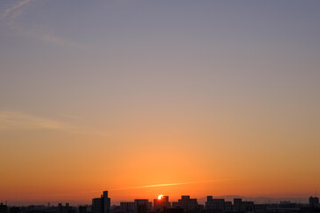 都会の夜明け。神戸市街地からの日の出。オレンジ色に染まる空と雲。神戸市街地から芦屋大阪方面を臨む