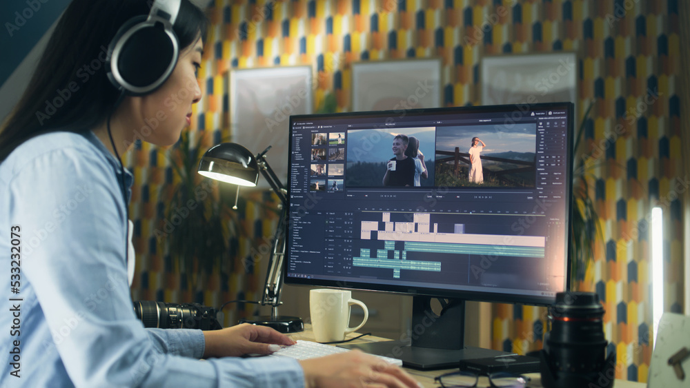 Poster concentrated asian woman sitting at the table and editing video for client in professional software 