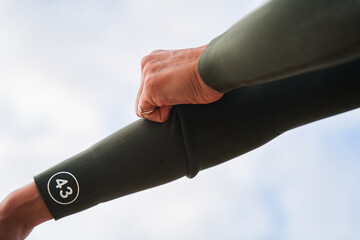 Fmale person adjusting sleeves of her green wetsuit