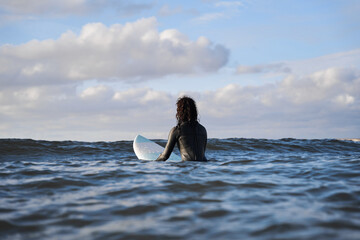 Surfer girl swimming with board at the wavy ocean