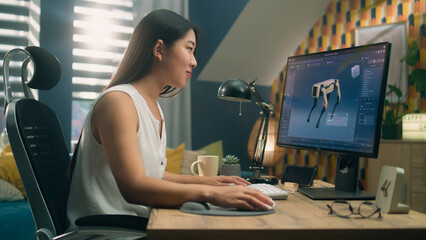 Obraz na płótnie Canvas Asian woman working on pc in 3D modeling program remotely from home office and creating 3D prototype of modern robot