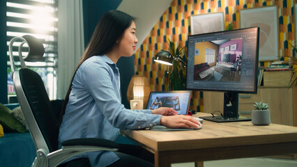 Female asian designer working remotely from home office and making 3D visualization of house...