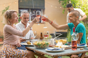 Group friends toasting with big smile around the table at house patio diner.