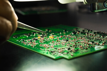 Manual assembly of electric components onto green PCB. Closeup shot of a hand of unrecognizable...