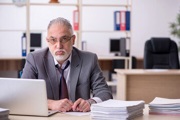 Obraz premium Old male employee unhappy with excessive work in the office