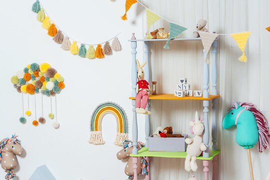 white bookcase in the children's room with toys. bright room for a child with toys of horses and wooden houses. children's photo zone in the photo studio