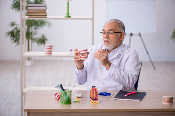 Old male dentist working in the clinic
