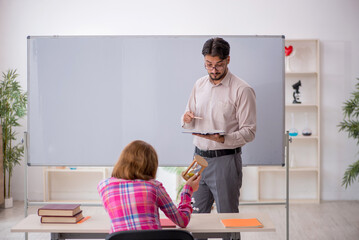 Young male teacher and redhead girl in the classroom