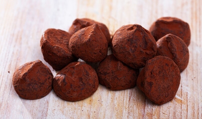 Heap of delicious chocolate truffles in cocoa powder on wooden surface..
