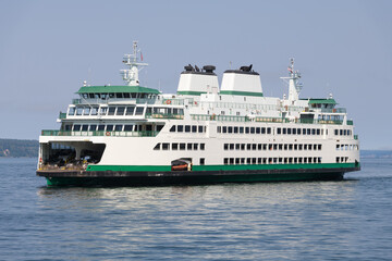 Green and white car ferry on calm water during day with blue sky