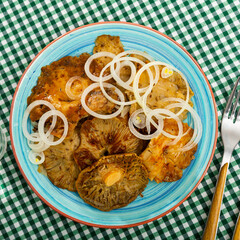 Appetizing juicy pickled russula delica, sprinkled on top of onion rings on a plate - obrazy, fototapety, plakaty