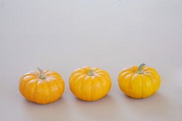 Three Orange Pumpkins in a Row on Beige Background