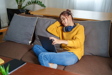 Fototapeta premium Portrait of a young Asian woman using a computer on the sofa