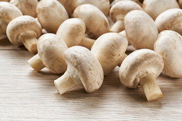whole champignon mushrooms on a white wooden background close-up.