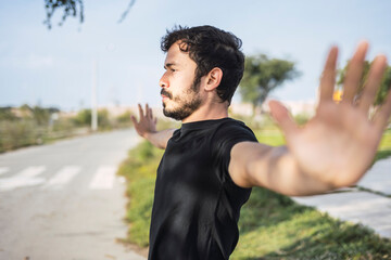 Getting ready to do his best. Portrait of a sporty young man stretching his arms while exercising outdoors.