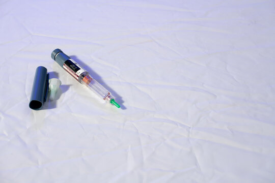 Insulin pen and glucose meter on white background.
