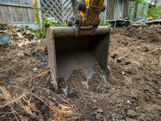 close up of mini digger bucket excavating the ground in a garden work site