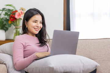 Obraz na płótnie Canvas Recruitment Concept. Girl Browsing Work Opportunities Online on sofa at home, Happy Asian woman Using Job Search App or Website on Laptop, Copy Space
