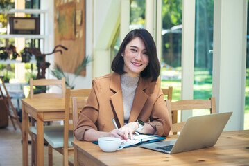 Happiness Asian Woman working from home using laptop online meeting in home office. Happy relax time asian business woman typing keyboard use notebook laptop Smiling, laughing, yawn at home office.