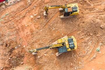 Excavator on earthmoving at construction site, aerial view.