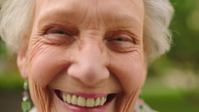 Portrait of a happy elderly woman in an outdoor garden at an old age house during spring time. Positive senior lady laughing while standing outside in nature for fresh air, happiness and wellness.