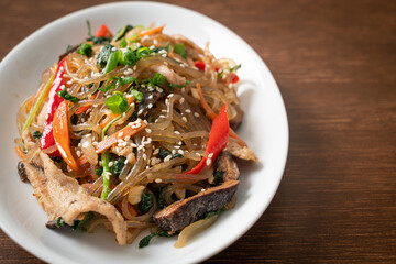 japchae or stir-fried Korean vermicelli noodles with vegetables and pork topped with white sesame