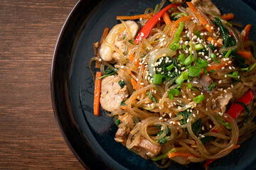 japchae or stir-fried Korean vermicelli noodles with vegetables and pork topped with white sesame