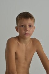 A serious blond tanned boy sits and looks straight ahead.