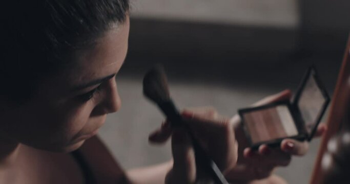 Close up of young woman applying make up with a brush.