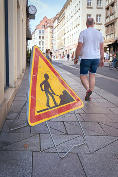 Baustellenschild und Passant auf einem Fußweg in der Innenstadt von Straßburg in Frankreich
