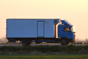 Cargo truck driving on highway hauling goods in evening. Delivery transportation and logistics concept