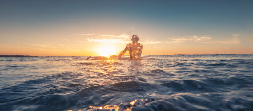 Surfer entering the ocean at sunset