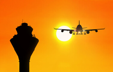 Airport traffic control tower with an airplane approaching at sunset