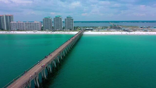 Aerial view flying down the Navarre Beach FL Pier looking at the beautiful white sand, board walk, and the water tower.