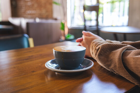 Closeup image of a woman and a cup of hot coffee on wooden table