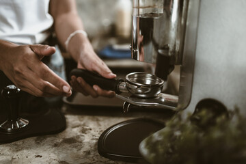 barista use bottomless filter with grinder machine at coffee shop. coffee maker concept.