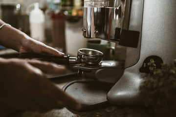 barista use bottomless filter with grinder machine at coffee shop. coffee maker concept.