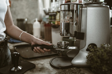 barista use bottomless filter with grinder machine at coffee shop. coffee maker concept.