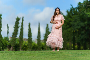 cheerful pregnant woman standing in park