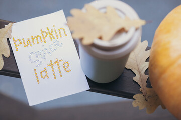 autumn coffee in a mug with pumpkins and oak leaves, on the background of the phrase from rhinestones Pumpkin spice latte