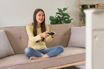 Leisure activity concept, Young woman sitting on couch to control joystick while playing video game