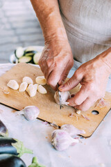 A woman is cooking, cutting garlic. Processing organic fresh garlic. Close-up selective focus