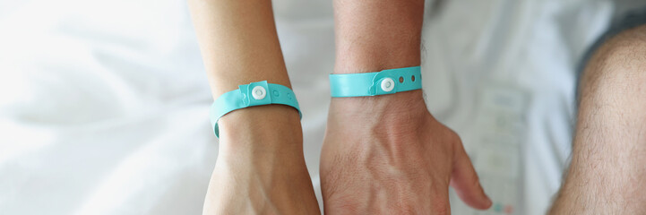 On the male and female hands a blue hotel bracelet