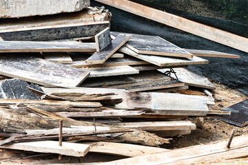 Construction waste after dismantling the formwork of a reinforced concrete foundation. Utilization of construction waste. Old boards, beams and formwork panels at a construction site.