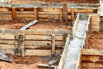 Fototapeta na wymiar Reinforced concrete foundation of a modern monolithic residential building. Prepared formwork with reinforcing mesh for pouring concrete. Dirt and clay at the construction site.