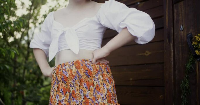 Midsection of woman performing belly dance. Young female wearing casuals is dancing gracefully against log cabin. She is spending leisure time in forest.