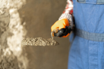 Hands man plasterer construction worker at work with trowel, plastering a wall cement mortar