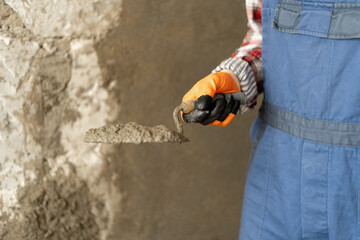 Hands man plasterer construction worker at work with trowel, plastering a wall cement mortar