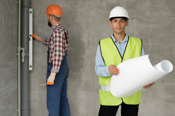 construction site engineer or architect with blueprints and builder with level in hands....
